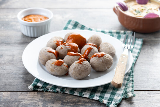Papas arrugadas with mojo and gofio escaldado on wooden table. Traditional Canary Islands food.