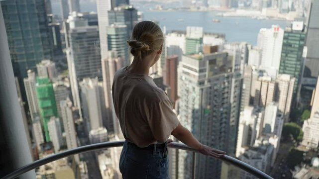 Woman in elevator in the skyscraper of Hong Kong with the view of city panorama with tall buildings in downtown. Concept of tourist visiting HongKong, viewpoint in urban city