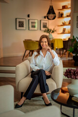 Obraz premium Full length of a brunette haired woman sitting in an armchair and cheerful smiling