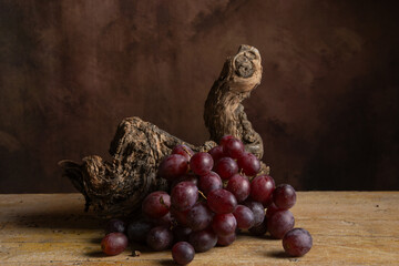 Top view of bunch of red grapes on vine trunk, dark background, horizontal with copy space