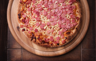 Pizza with ham and mozzarella cheese on wooden background. Soft focus. Close up	