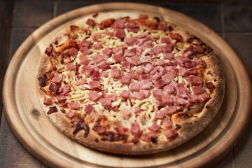 Pizza with ham and mozzarella cheese on wooden background. Soft focus. Close up	