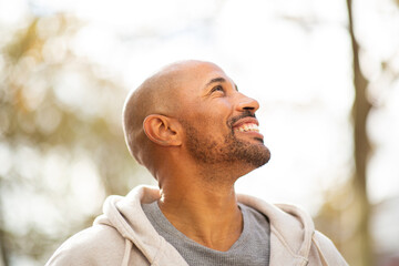 cheerful man looking up towards the sky with a hopeful expression.