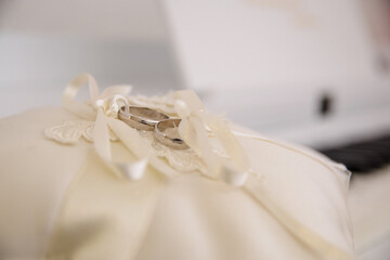 Elegant white gold wedding rings on a light brown decorative cushion