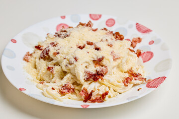 a portion of pasta carbonara on a plate on a table