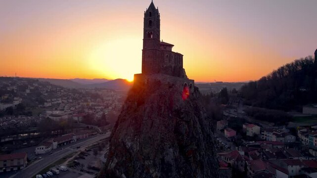 aerail shot revealing the Saint Michel d'Aiguilhe rock and chapel at sunrise in le Puy en Velay, haute loire department, auvergne rhone alpes region, france