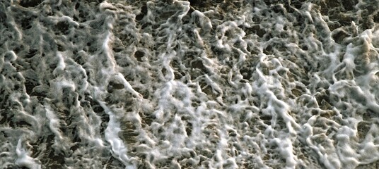 Top view. Foam on the ocean shore. Waves on the water. Contrasting image. Moody colors. Soft textured background