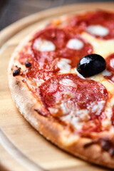 Pizza with salami and mozzarella cheese. Wooden background. Soft focus. Close up.	