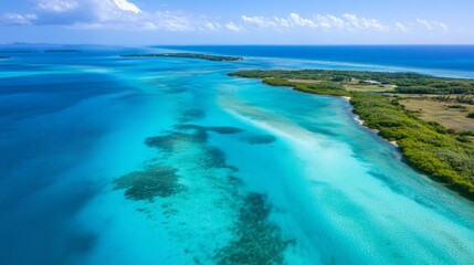 Aerial view of a tropical lagoon, with shallow turquoise waters transitioning into deep blue ocean.