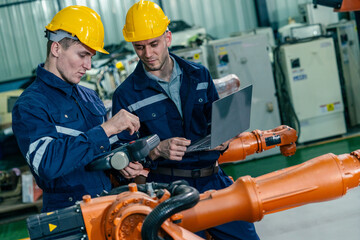 Skilled workers using technology to monitor robotic systems in a modern manufacturing facility during the day
