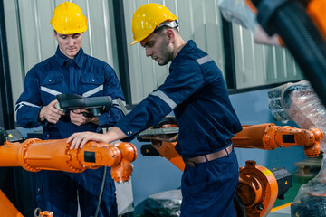 Engineers working on robotic arms in a modern industrial facility with safety helmets and equipment