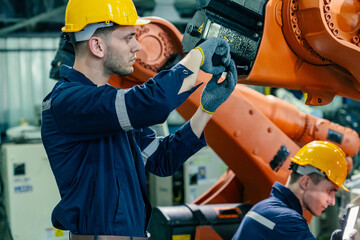 Skilled workers maintain robotic equipment in a manufacturing facility during daytime