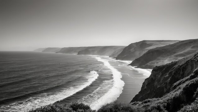 Serene Black and White Coastal Landscape with Rolling Waves and Rugged Cliffs Under a Hazy Sky