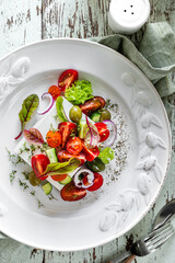 Fresh Greek salad in a white plate on a wooden background. Mediterranean cuisine