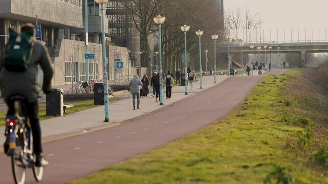 A lively urban cycling and walking path with people commuting, biking, and strolling in Amsterdam