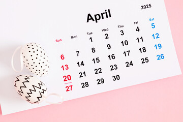 Close-up of a desk paper calendar sheet for April 2025 with Easter date highlighted and Easter decor