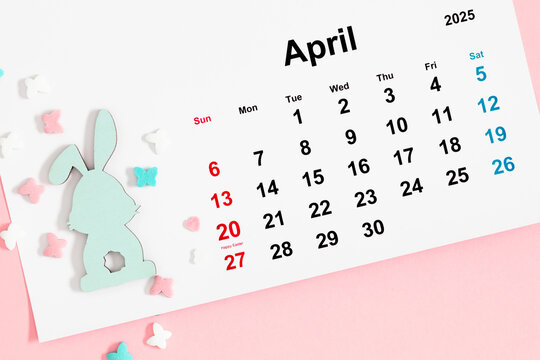 Easter composition. Top view of a paper calendar sheet for April 2025, with a mark for the 20th and with a cute funny Easter bunny and sugar candies.