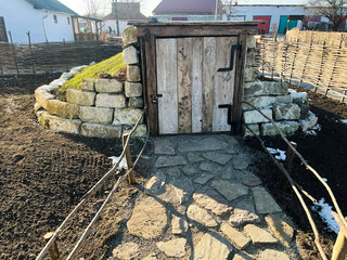 Rustic grass-roofed storage hut surrounded by natural stone walls and fences