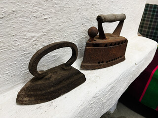 Vintage rustic flatirons showcased on a white surface in a homely environment