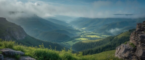 Fototapeta premium Majestic Mountain Landscape with Fog Over Green Valley Under Clear Blue Sky