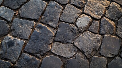 Fototapeta premium A close-up view of weathered cobblestone pavement featuring various shades of gray and textured surfaces, creating a rustic and historical feel.