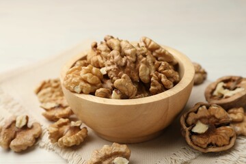 Peeled walnuts in bowl on light table, closeup