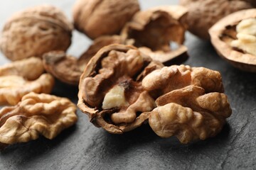 Fresh ripe walnuts and shells on black table, closeup