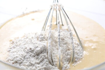 Whisk and bowl of dough, closeup view