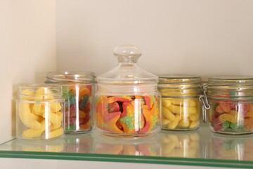 Tasty gummy candies in jars on shelf