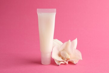 Lip balm and flower on pink background, closeup