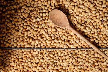 Chickpeas spread out with wooden spoon resting above, captured in warm natural light showcasing their earthy texture and color