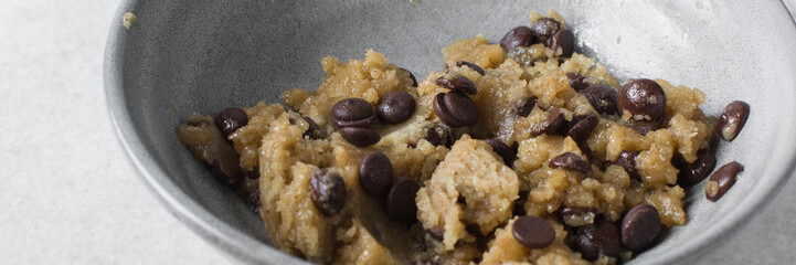 Overhead view of chocolate chip cookie dough, top view of homemade chocolate chip cookie dough in a bowl on a white background, process of making chocolate chip cookie
