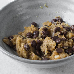 Overhead view of chocolate chip cookie dough, top view of homemade chocolate chip cookie dough in a bowl on a white background, process of making chocolate chip cookie