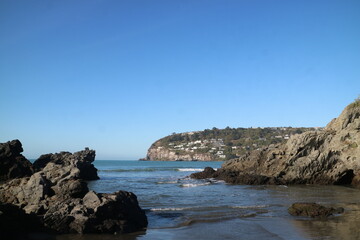 A rugged coastal scene in New Zealand with cliffs, blue waters, and a clear sky. A stunning natural landscape that captures the beauty of untouched shorelines.