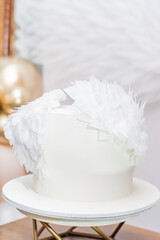 Beautiful white baptism cake adorned with soft feathers for a special celebration in a serene venue