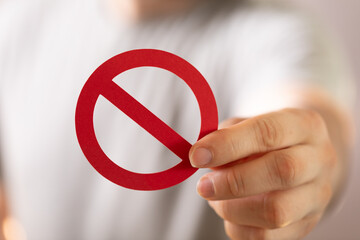 Person holding a red prohibition sign.  Concept of restriction, denial, or warning.