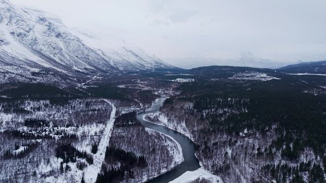 Snow-covered mountain landscape, a winding river through the forest in Norway