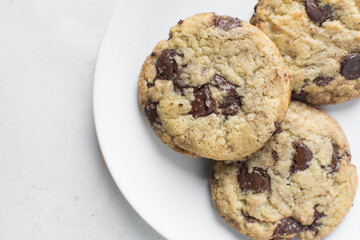 Overhead view of chocolate chip cookies on white plate, top view of homemade chocolate chip cookies on a white background