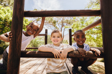 Obraz premium Smiling children playing on a wooden playground outdoors on a sunny day