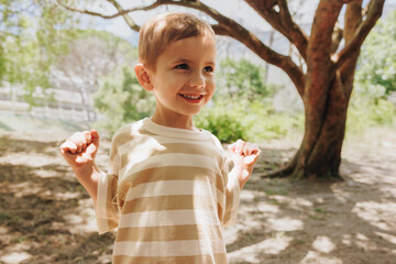 Cheerful young boy smiling outdoors under trees on a sunny day