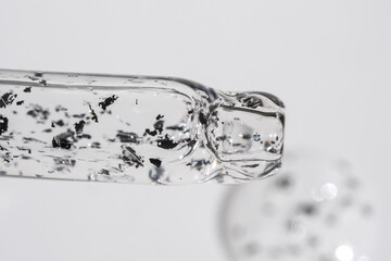 Glass pipette with cosmetic liquid with silver particles.