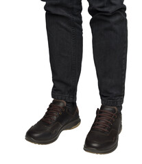 Man's legs in dark jeans are shown wearing dark brown leather casual shoes. Isolated on transparent background