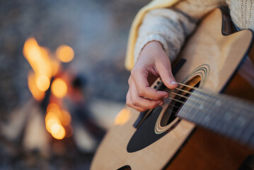 Close up of hands of a young girl while playing the guitar. Spending time on nature playing guitar,...