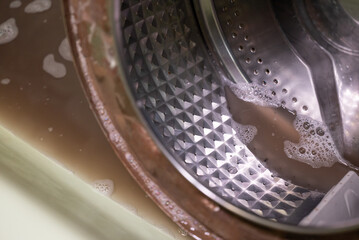 Cleaning washing machine concept. Drum of washing machine in bath, dirty water, cleaning parts, service of washer