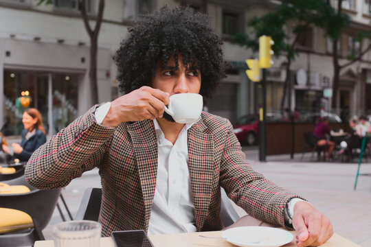 Mixed race man teleworking while enjoying coffee outdoors