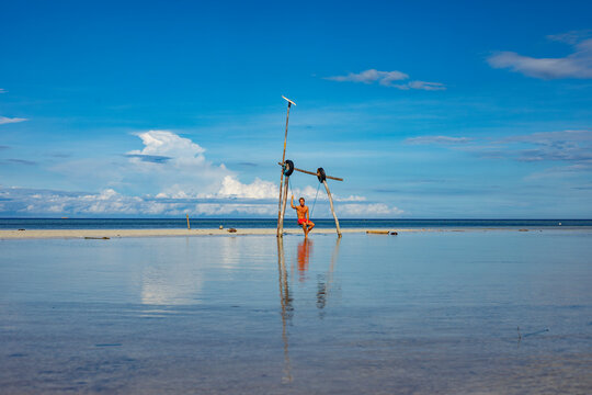 Man swinging on makeshift swing at Philippine beach