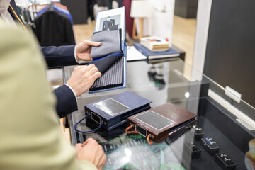 Tailor discussing fabric options for custom suit design in suit store
