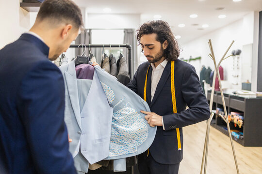 Tailor Showcasing Custom Suit to Client for Perfect Fit in suit store