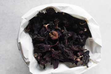 Overhead view of dried roselle in a white paper bag, top view of dried hibiscus and Sorrel flowers, ingredient for making nigerian zobo drink
