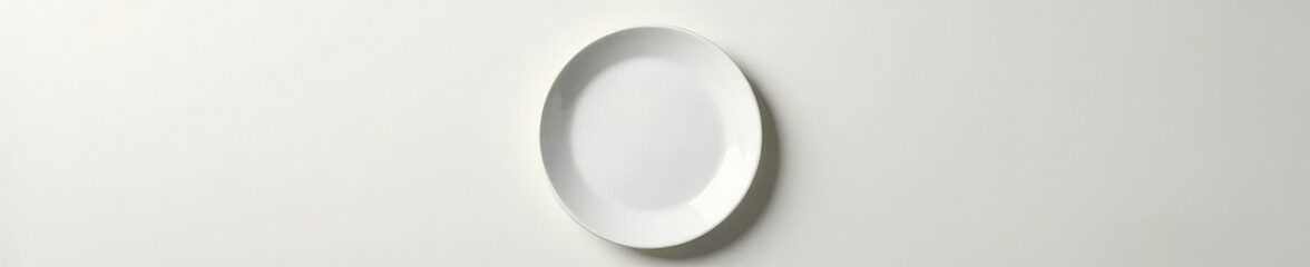 A single white plate placed on a plain surface with a few objects around it, clean, plate